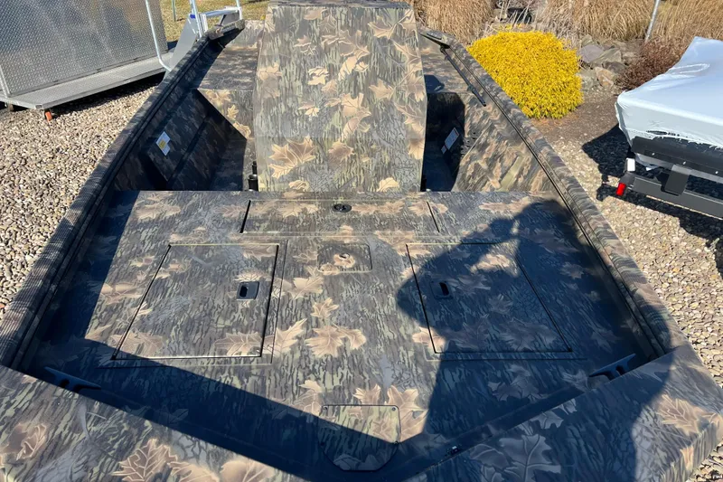 Slide: The Image of 2025 Crestliner 1660 Retriever FCC boat with camouflage pattern, parked on gravel. - 5