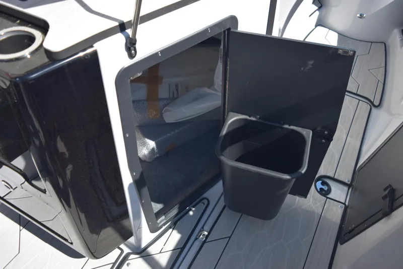 Slide: The Image of 2024 Yamaha Boats 222XD storage compartment with trash bin. - 14