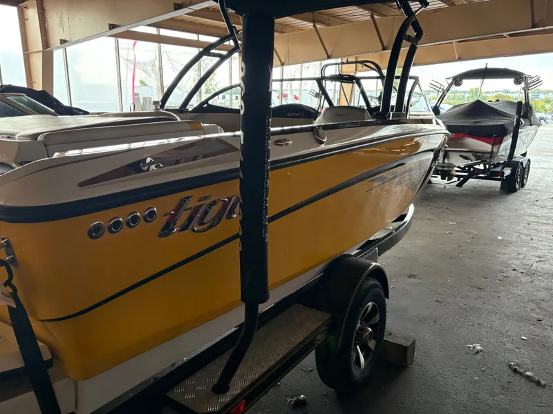 Slide: The Image of 2014 Tigé R20 yellow boat on trailer in a covered storage area. - 1