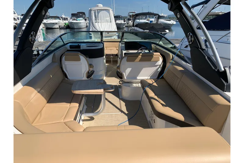 Slide: The Image of 2023 Sea Ray SLX 280 boat interior with beige seating and table, docked at marina. - 5