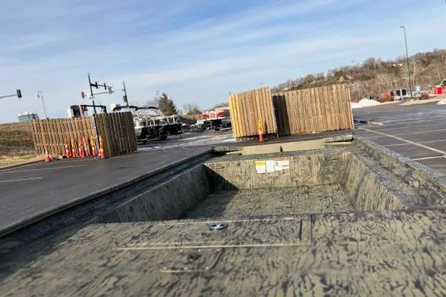 Slide: The Image of 2026 Tracker Grizzly 1754 Utility boat in a parking lot, surrounded by construction materials. - 28