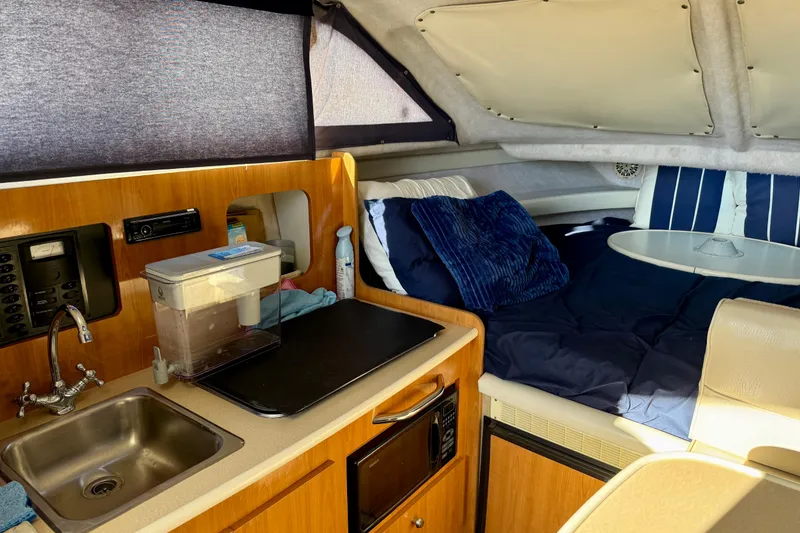 Slide: The Image of 2002 Bayliner 2452 Ciera Classic cabin interior with kitchenette and cozy sleeping area. - 8