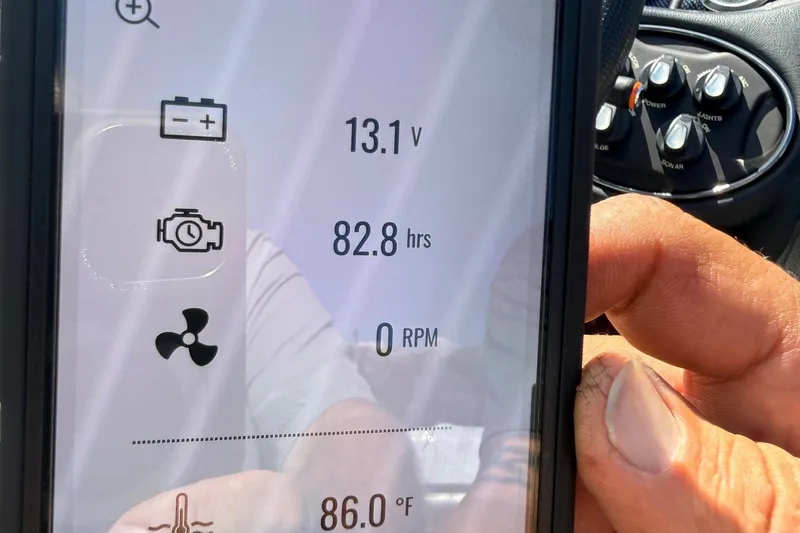 Slide: The Image of Close-up of a smartphone displaying boat engine metrics, including voltage and engine hours. - 32