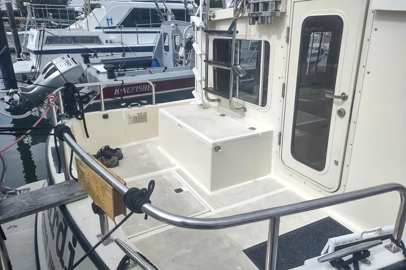Slide: The Image of 2004 Nordic Tug 32 boat deck with seating and access door at marina. - 14