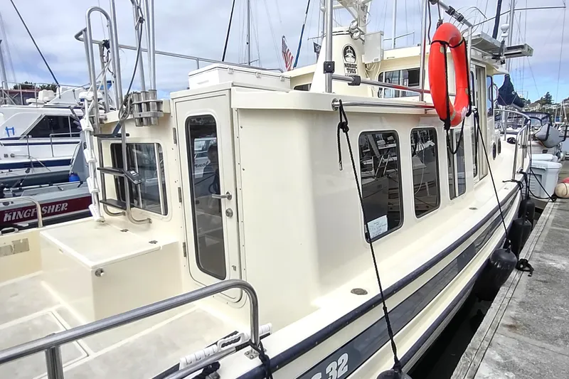 Slide: The Image of 2004 Nordic Tug 32 docked, featuring a cream exterior and red life preserver. - 16
