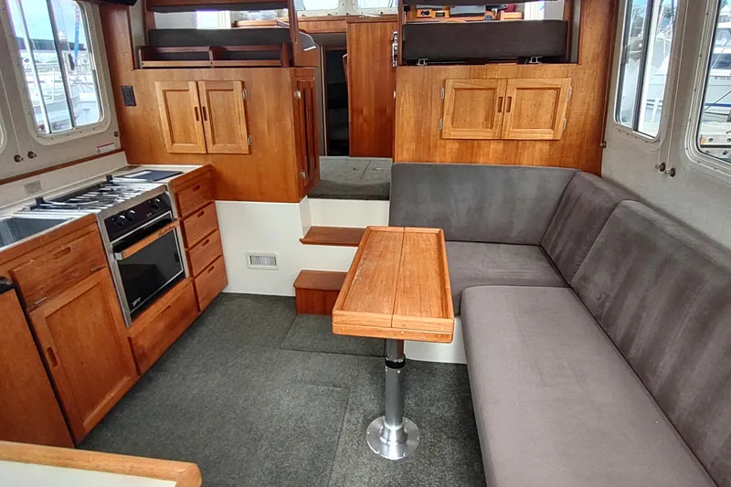 Slide: The Image of 2004 Nordic Tug 32 interior with wood cabinetry, compact kitchen, and cozy seating area. - 18