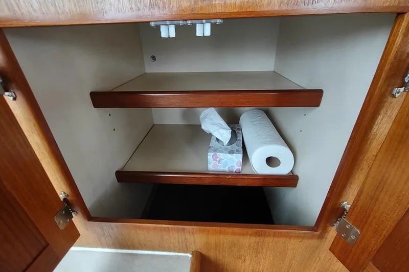 Slide: The Image of Open wooden cabinet with shelves, tissue box, and paper towel roll on a 2004 Nordic Tug 32. - 22