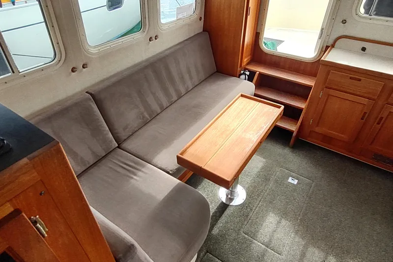 Slide: The Image of Interior of 2004 Nordic Tug 32 with sofa, wooden table, and cabinetry. - 25