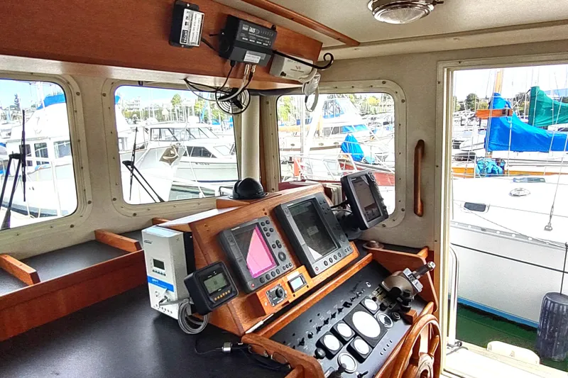 Slide: The Image of Interior helm of 2004 Nordic Tug 32 with navigation equipment and marina view. - 28