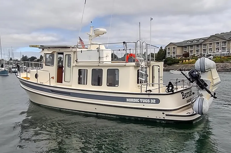 Slide: The Image of 2004 Nordic Tug 32 boat docked near a waterfront hotel. - 3