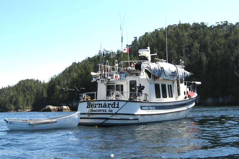 Slide: The Image of 2004 Nordic Tug 32 boat anchored in scenic waters with forested background. - 52