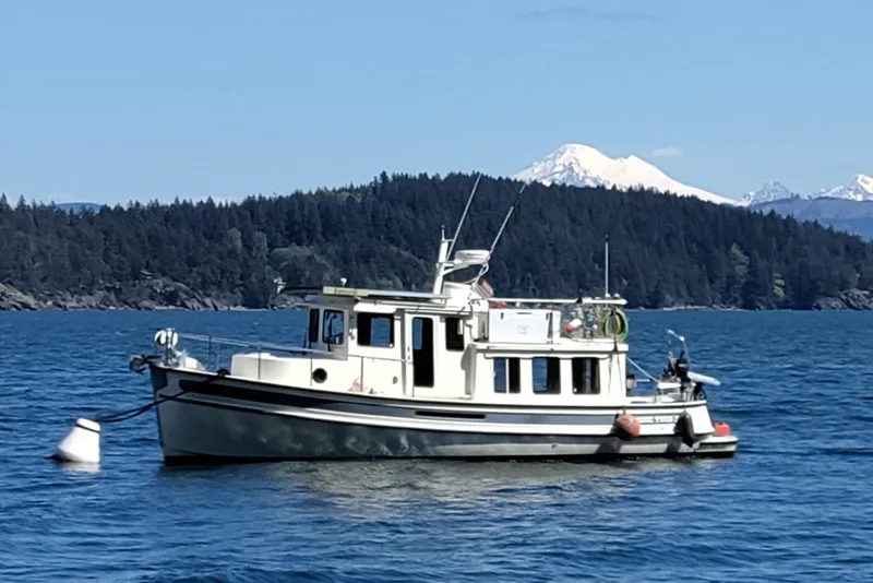 Slide: The Image of 2004 Nordic Tug 32 boat on scenic lake with forested mountains in background. - 54