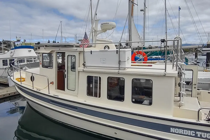 Slide: The Image of 2004 Nordic Tug 32 docked at marina, featuring classic design and American flag. - 6