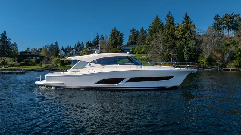 Slide: The Image of 2024 Riviera 505 SUV yacht cruising on a serene lake with lush greenery. - 31