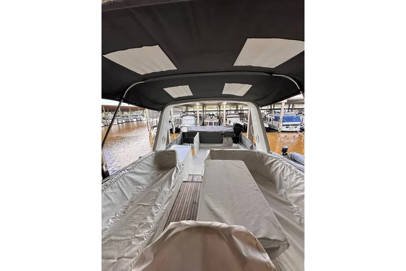 Slide: The Image of 2015 Beneteau Swift Trawler 50 interior with covered seating and canopy, docked at marina. - 13