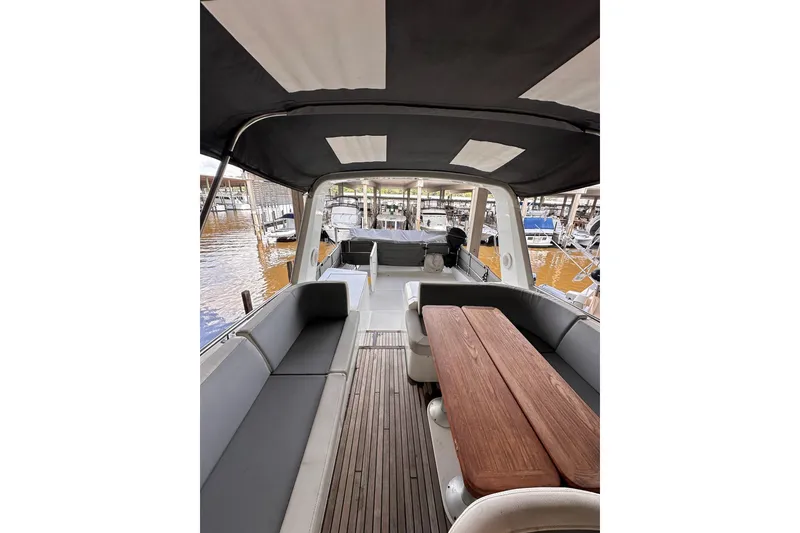 Slide: The Image of 2015 Beneteau Swift Trawler 50 interior with seating and wooden table, docked at marina. - 23