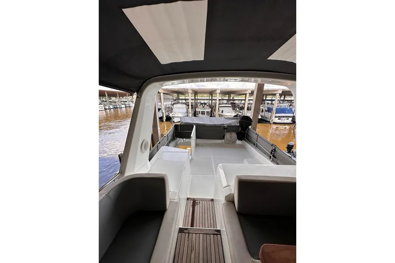 Slide: The Image of 2015 Beneteau Swift Trawler 50 interior view at marina, showcasing seating and deck area. - 27