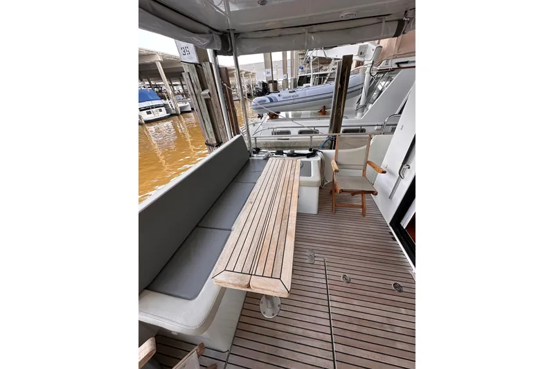 Slide: The Image of 2015 Beneteau Swift Trawler 50 deck with seating and wooden table, docked at marina. - 34