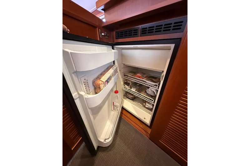 Slide: The Image of Open refrigerator inside 2015 Beneteau Swift Trawler 50, stocked with food items. - 55