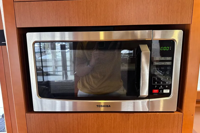 Slide: The Image of Toshiba microwave in 2015 Beneteau Swift Trawler 50 kitchen, wood paneling background. - 60