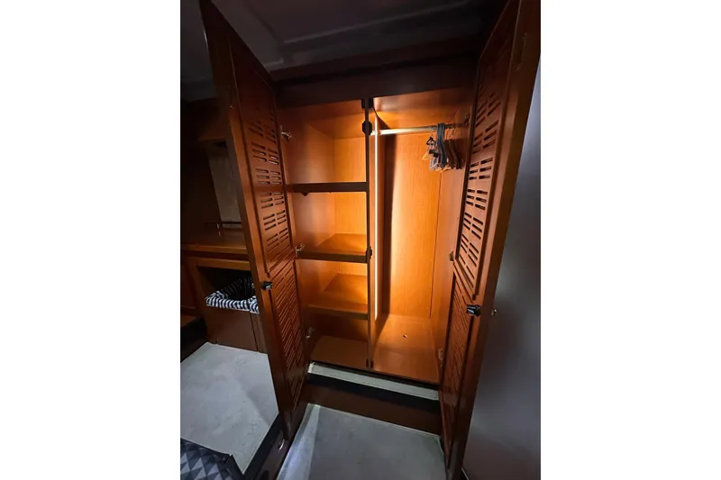 Slide: The Image of Wooden closet interior on 2015 Beneteau Swift Trawler 50, featuring shelves and hangers. - 87