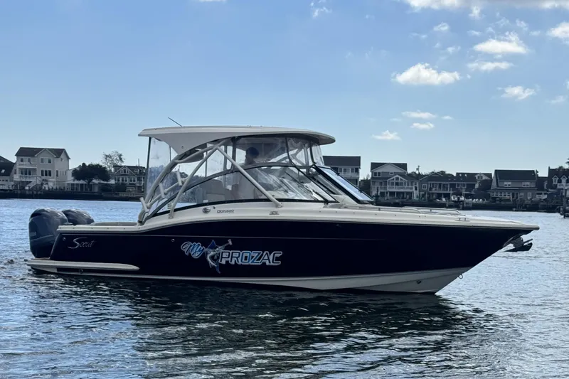 The Image of 2020 Scout 255 Dorado boat on water, houses in background, clear sky. - 0