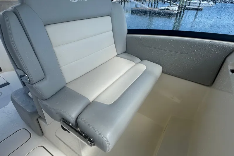 Slide: The Image of 2020 Scout 255 Dorado boat seat with gray and white upholstery, near water. - 11
