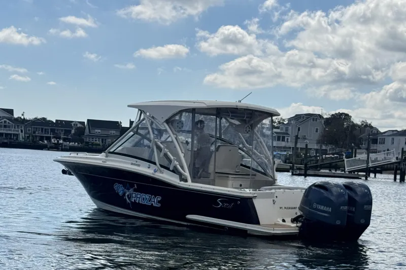 Slide: The Image of 2020 Scout 255 Dorado boat on water, houses in background, clear sky. - 2
