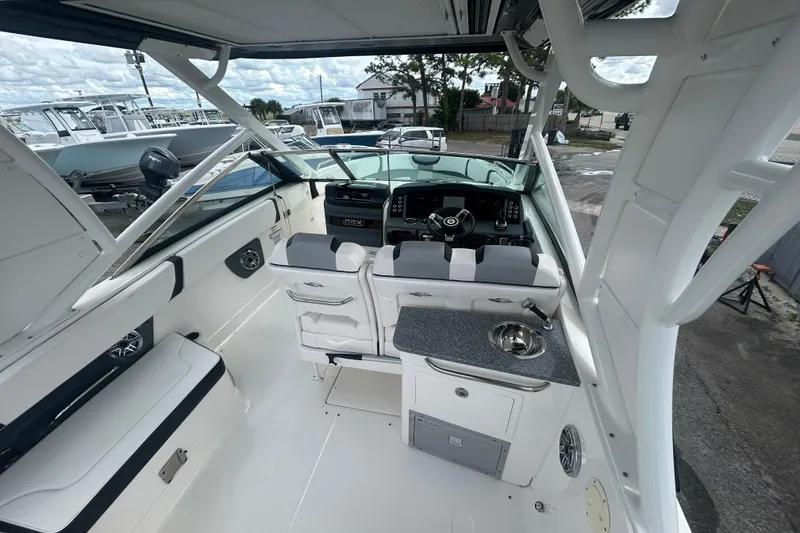 Slide: The Image of 2021 Chaparral 280 OSX boat interior with helm, seating, and kitchenette. - 10