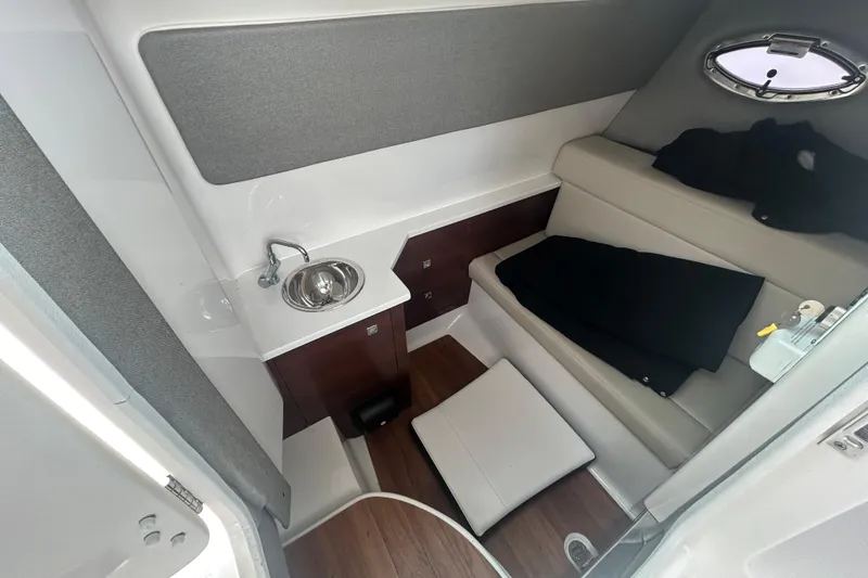 Slide: The Image of 2021 Chaparral 280 OSX cabin interior with sink, seating, and porthole window. - 20