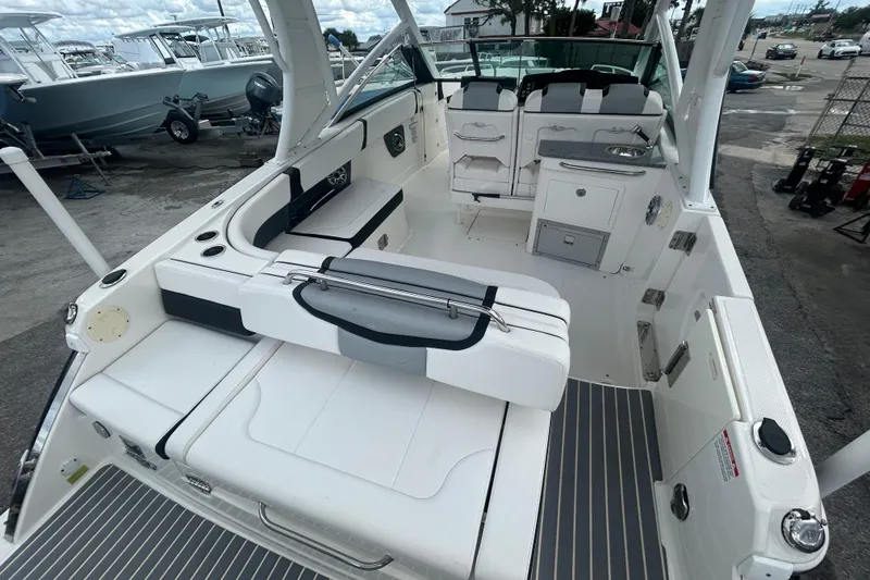Slide: The Image of 2021 Chaparral 280 OSX boat interior with seating and kitchenette, docked outdoors. - 9