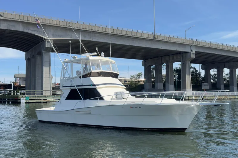 Slide: The Image of 1989 Viking 41 Convertible yacht cruising under a bridge on a sunny day. - 15