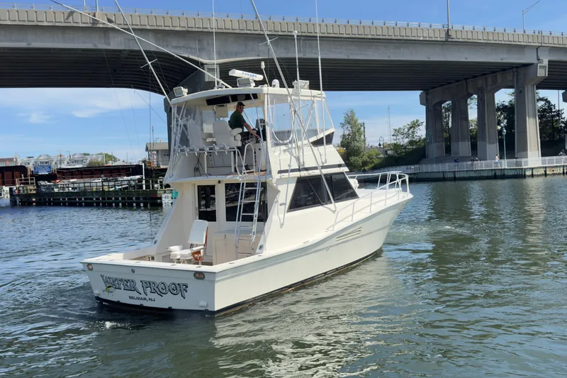 Slide: The Image of 1989 Viking 41 Convertible boat cruising under a bridge in a marina setting. - 16