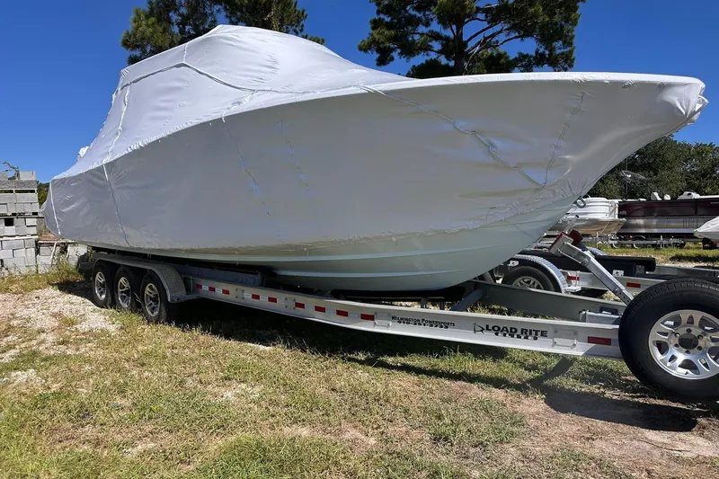 The Image of 2026 Sportsman Heritage 321 Center Console boat covered on trailer, parked outdoors. - 0