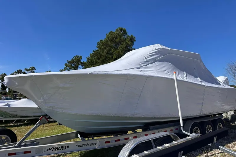 Slide: The Image of 2026 Sportsman Heritage 321 Center Console boat covered on trailer, outdoors under blue sky. - 11