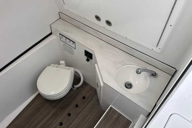Slide: The Image of 2026 Sportsman Heritage 321 Center Console bathroom with toilet and sink, modern design. - 60