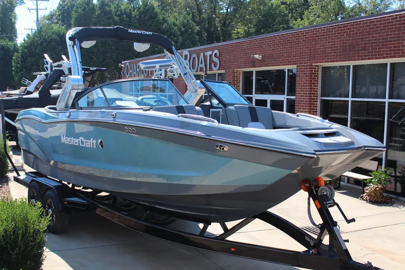 The Image of 2023 MasterCraft X24 boat on trailer outside dealership, showcasing sleek design. - 1
