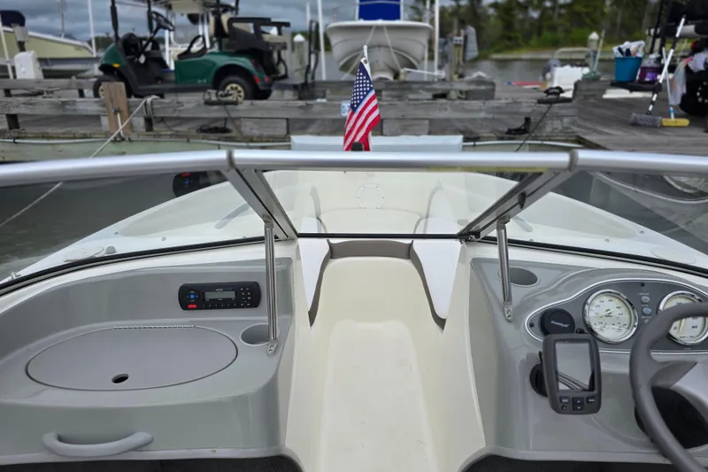 Slide: The Image of 2011 Bayliner 180 Bowrider dashboard with American flag, docked at marina. - 12