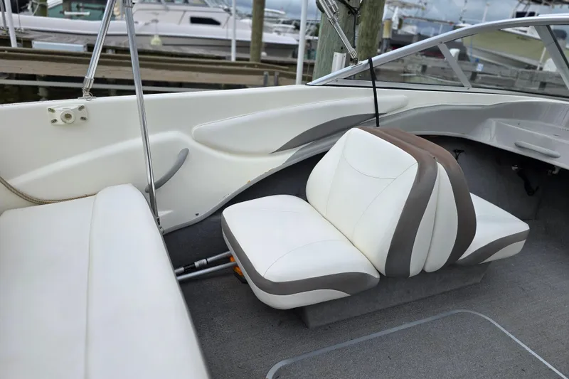 Slide: The Image of 2011 Bayliner 180 Bowrider interior with white and gray seating, docked at marina. - 16