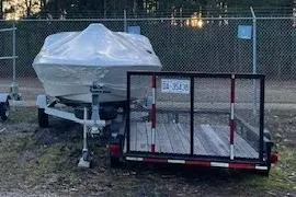 Slide: The Image of 2011 Bayliner 180 Bowrider boat covered, parked beside a utility trailer. - 24