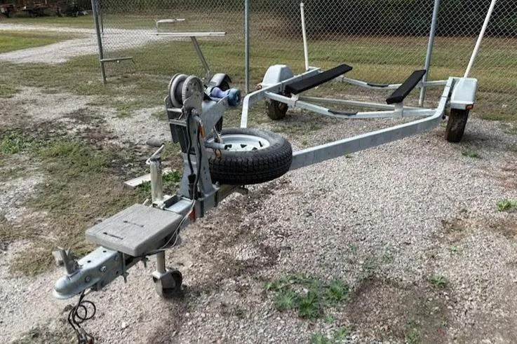 Slide: The Image of Boat trailer for 2011 Bayliner 180 Bowrider on gravel near chain-link fence. - 25