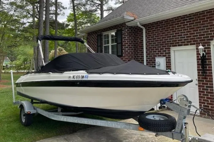 Slide: The Image of 2011 Bayliner 180 Bowrider boat on trailer, covered, parked beside brick house. - 4