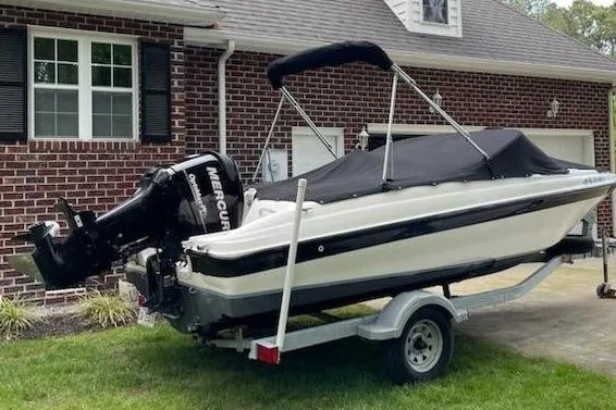 Slide: The Image of 2011 Bayliner 180 Bowrider boat on trailer, parked near brick house. - 5