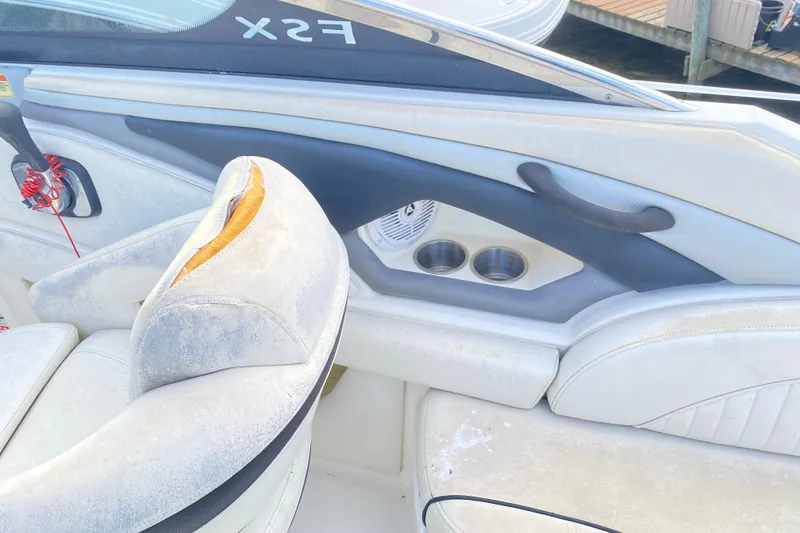 Slide: The Image of 2007 Monterey 234FSX boat interior with worn white seats and cup holders. - 13