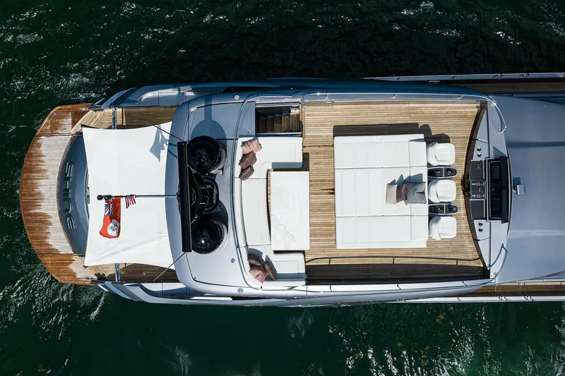 Slide: The Image of Luxurious 2022 Pershing 9X yacht deck with sun loungers and table, overlooking scenic waterfront. - 23