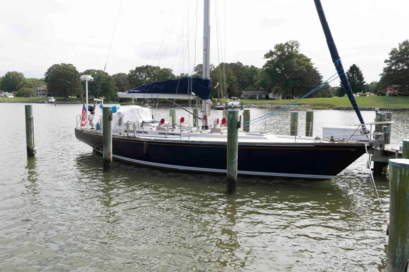 The Image of 1979 Hinckley 43 Sloop docked on a calm lake with trees in the background. - 0