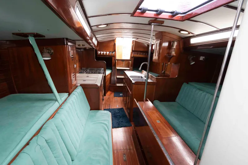 Slide: The Image of Interior of a 1979 Hinckley 43 Sloop, featuring wood finishes and teal seating. - 12