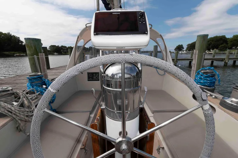 Slide: The Image of 1979 Hinckley 43 Sloop cockpit with steering wheel and navigation equipment, docked by the water. - 5
