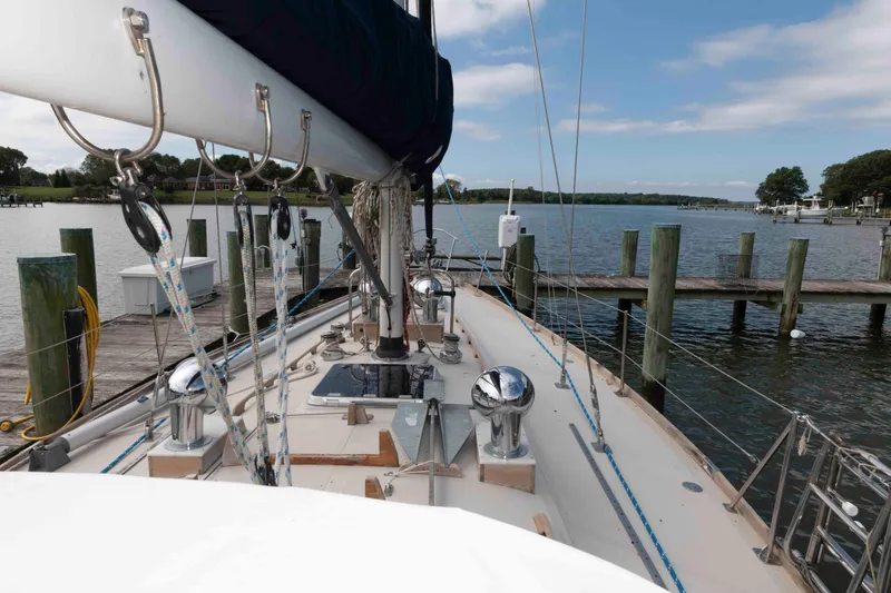 Slide: The Image of 1979 Hinckley 43 Sloop docked at a serene marina with clear skies. - 7