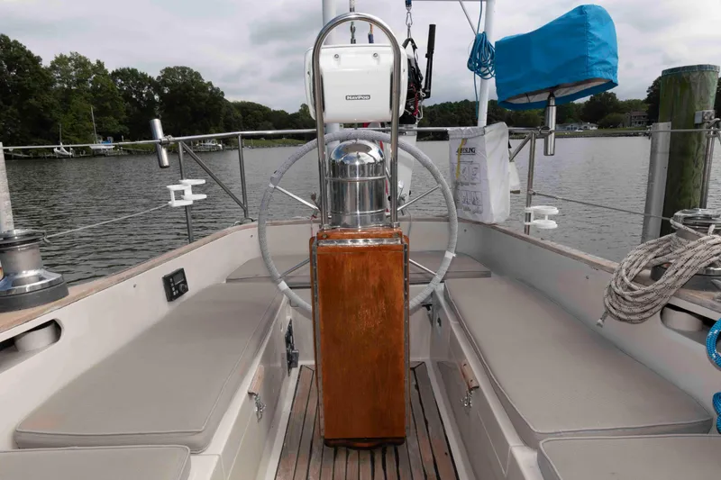 Slide: The Image of Cockpit of 1979 Hinckley 43 Sloop with wooden helm, docked by a serene lake. - 8